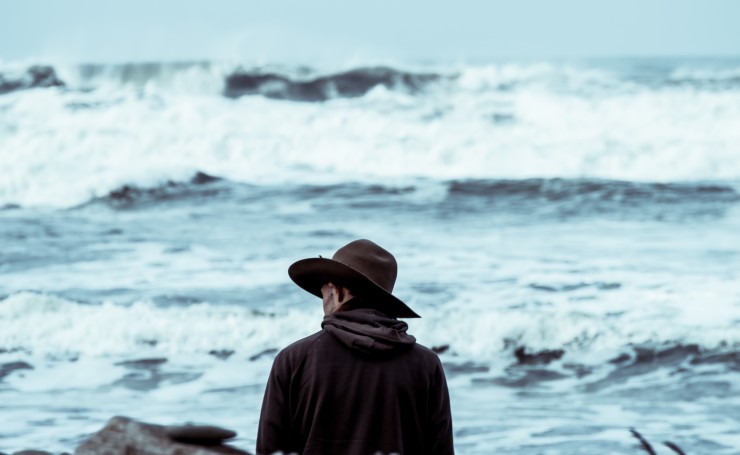 Мужчина в шляпе возле бурного моря