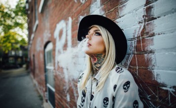 Блондинка с татуировками выдыхает дым