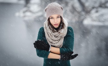 Девушка в шарфе, шапке и перчатках под снегом