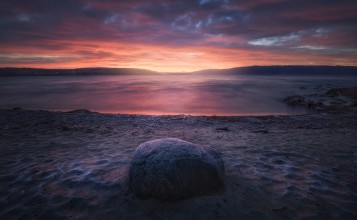 Камень на пляже на закате