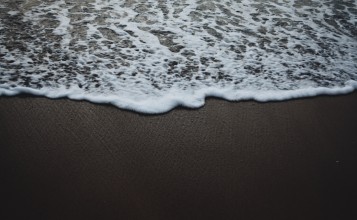 Морская пена на темном песке