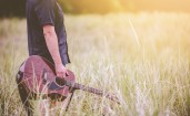 Мужчина с гитарой в поле