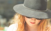 Рыжеволосая девушка в шляпе с прикрытым лицом
