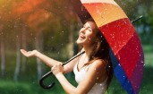 Счастливая брюнетка под дождем с зонтом
