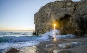 Свет солнца через скалу на берегу моря