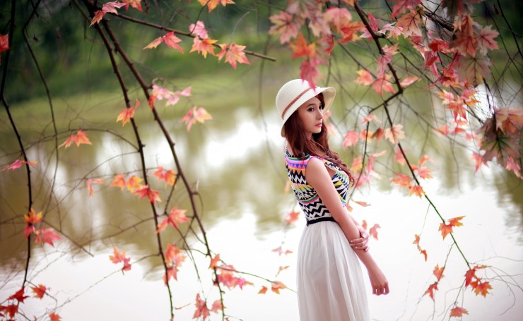 Девушка в платье и шляпке возле озера осенью