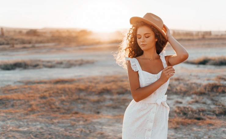 Девушка в шляпе и белом платье на фоне заката