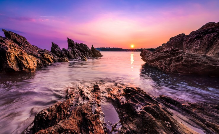 Красивый закат на каменистом берегу моря