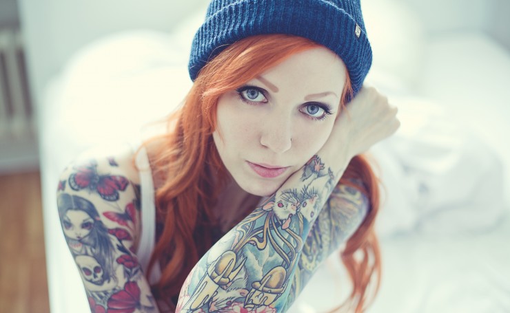Рыжеволосая девушка с татуировками на руках