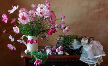 Букет розовых цветов и чемодан на столе