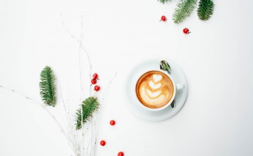 Чашка кофе на белом фоне, ягоды и еловые ветки