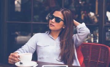 Девушка брюнетка в очках с чашкой кофе