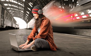 Девушка с ноутбуком сидит на платформе