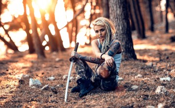 Девушка с татуировками и пирсингом сидит с мечом