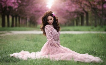 Девушка в розовом платье сидит на траве