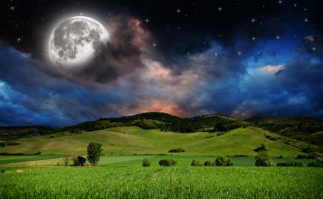 Луна в ночном небе над зелеными холмами