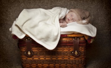 Маленький ребенок спит на чемодане