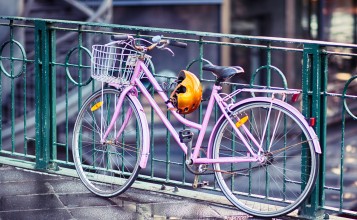 Розовый велосипед у ограды