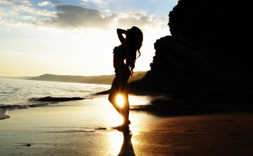 Силуэт девушки на пляже на фоне заката
