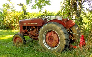 Старый красный трактор в траве