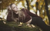 Девушка лежит на бревне в лесу