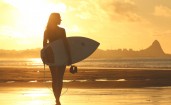 Девушка серфингистка на пляже на закате
