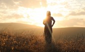Девушка в поле на фоне яркого солнца