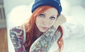 Рыжеволосая девушка с татуировками на руках
