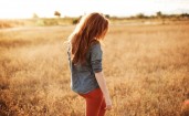 Рыжеволосая девушка в поле со спины