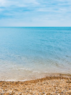 Каменистый пляж и синее море 240x320