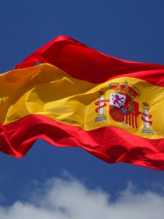 Развевающийся испанский флаг на фоне неба 240x320